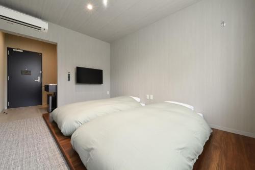 a bedroom with two white beds and a flat screen tv at Hotel Yatsu in Komatsu