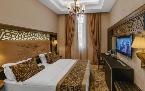 a bedroom with a large bed and a television at Gabala Karvansaray Hotel in Gabala