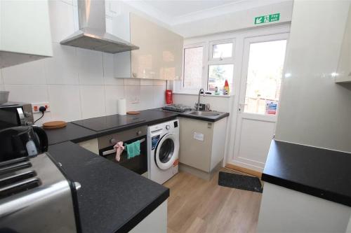 a kitchen with a washing machine and a washer at Spacious Double Room - Central Dartford in Dartford