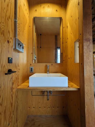 a bathroom with a white sink and a mirror at コワーキングスペース kuzume Base ゲストハウス 古朴-MOKU-1棟貸の宿 in Konan