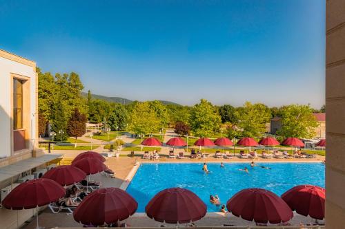 a large swimming pool with red umbrellas and people in it at Gabala Karvansaray Hotel in Gabala