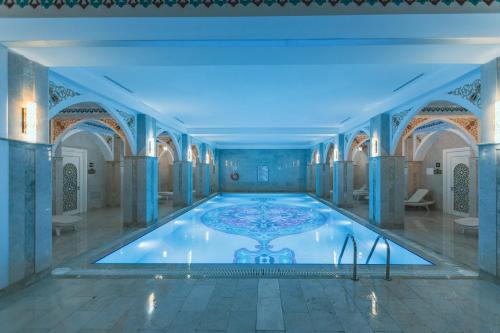 a large swimming pool in a room with blue tiles at Gabala Karvansaray Hotel in Gabala