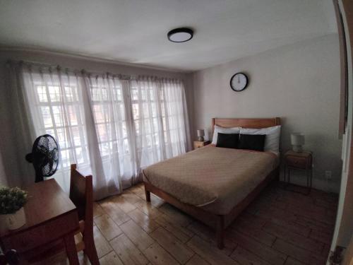 a bedroom with a bed and a clock on the wall at Casa Mazonce in Mexico City