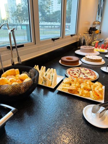 a table topped with different types of bread and pastries at Hotel Salute in Taguatinga
