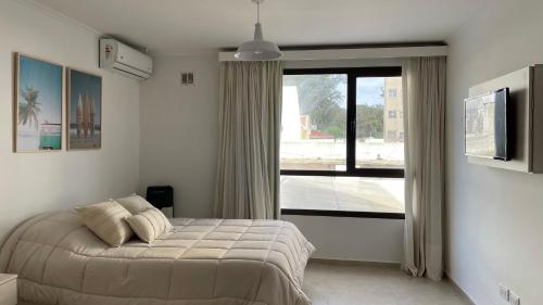 a bedroom with a bed and a large window at Aire de Mar Alojamiento Necochea in Necochea