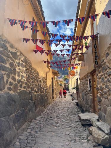 an alley with flags and people walking down a street at Rumi Wasi Inn Ollantaytambo in Ollantaytambo