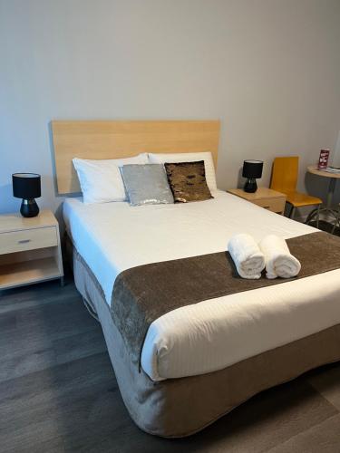a bedroom with a large bed with towels on it at Caloundra Central Apartment Hotel Official in Caloundra