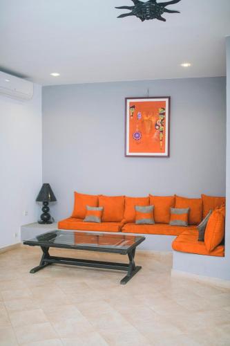 a living room with an orange couch and a coffee table at Modern villa with pool views in Ngaparou