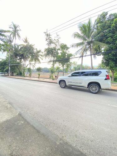 a white suv parked on the side of a road at Luang Prabang Golden Lotus Villa River View in Luang Prabang