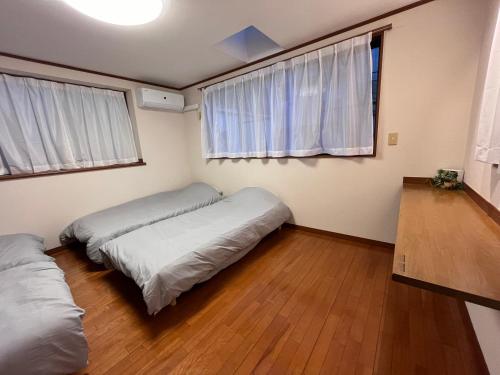 a bedroom with two beds and two windows at にじいろ邸東京大島駅前 in Tokyo