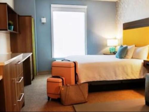 a hotel room with a bed with two luggage at Home2 Suites By Hilton Hayward in Hayward