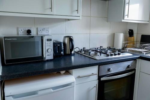 una cocina con microondas y estufa horno superior en 2bedroom sleeps 5 Raynes Park London 30min to Central London Family Friendly, en Raynes Park