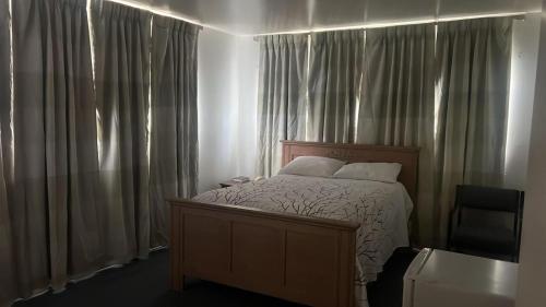 a bedroom with a bed and a chair and curtains at Economy Inn in Temple