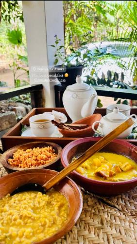 a table topped with bowls of food and tea pots at Zensigiri Ayurveda Wellness Homestay in Sigiriya