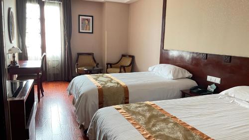 a hotel room with two beds and a desk at Seventh Heaven Hotel in Shanghai