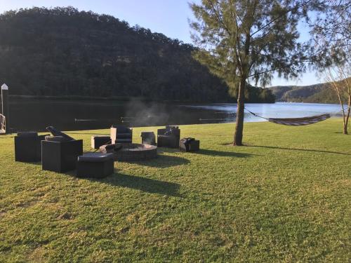 a fire pit in the grass next to a lake at Waterfront Double-Cabin Getaway in Wisemans Ferry