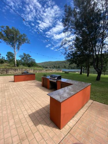 a barbecue grill sitting on a brick patio at Waterfront Double-Cabin Getaway in Wisemans Ferry