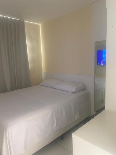 a white bed in a white room with a television at Apto 2 quartos com ar - Fechadura eletrônica - Até 8 pessoas in Petrolina