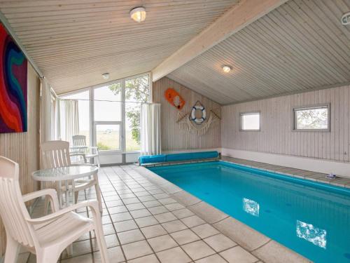 a swimming pool in a room with a table and chairs at Secluded Pool Retreat - By Traum Ferienwohnungen in Jerup
