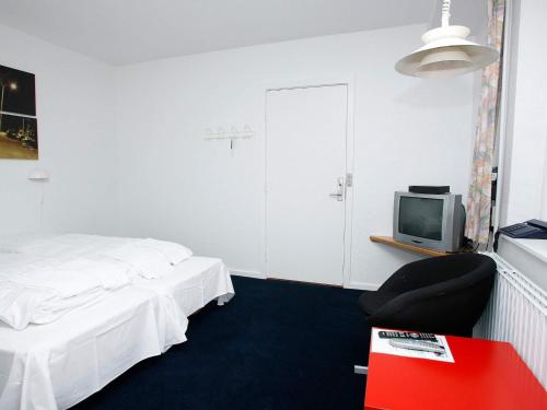 a room with a bed and a chair and a tv at Vigsø Holiday Center in Hanstholm