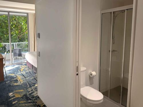 a bathroom with a toilet and a glass shower at Parkview Studio at Harbour Lights in Cairns
