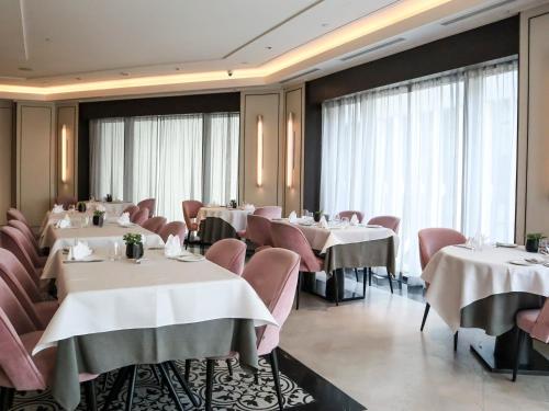 a restaurant with white tables and pink chairs at Grand Park City Hall in Singapore