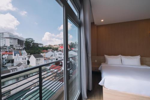 a room with a bed and a balcony with a view at HOANG LINH PHAT HOTEL in Da Lat