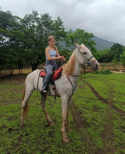a young woman riding a white horse in a field at Finca Montaña Sagrada in Mérida