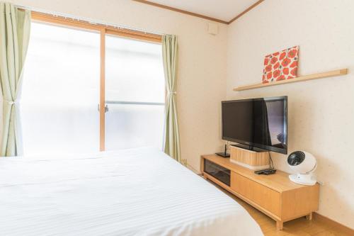a bedroom with a bed and a tv and a window at Ken House Kyoto in Kyoto