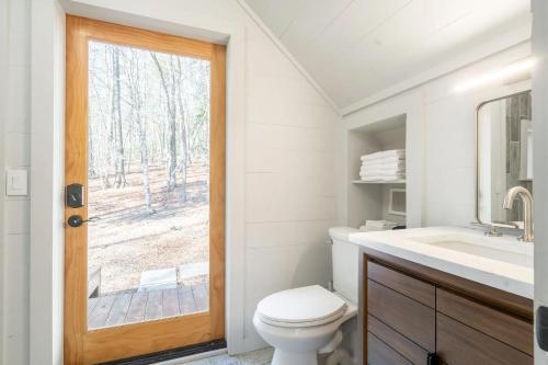 a bathroom with a toilet and a sink and a window at Aska's Cozy Corner Cabin in Cherry Log