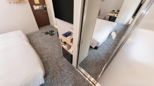 a mirror in a small room with a bed and a bed sqor at Super Hotel Premier Tokyo Station Yaesu-Chuoguchi in Tokyo