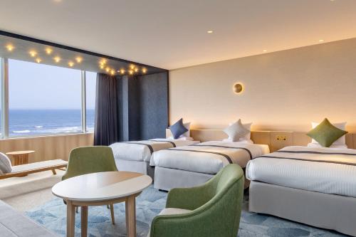 a hotel room with four beds and a table and chairs at KAMENOI HOTEL Kujukuri in Asahi