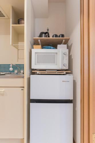 a microwave on top of a refrigerator in a kitchen at Ken Hotel Tokyo Shinjuku in Tokyo