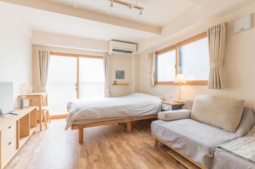 a bedroom with a bed and a couch and windows at Ken Hotel Tokyo Shinjuku in Tokyo