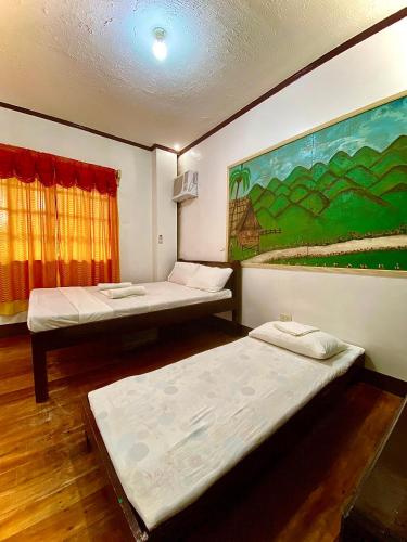 two beds in a room with a painting on the wall at Jala Beach Resort in Loay