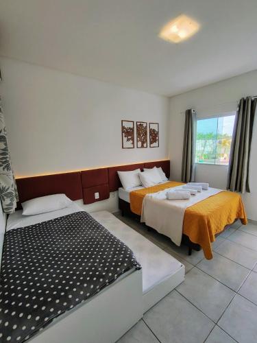 a hotel room with two beds and a window at Marlindo Hospedagem in Penha