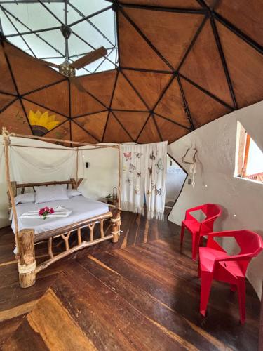 a bedroom with a bed and two red chairs at Mi casa es tu casa- Glamping y Casa de Campo in Capurganá