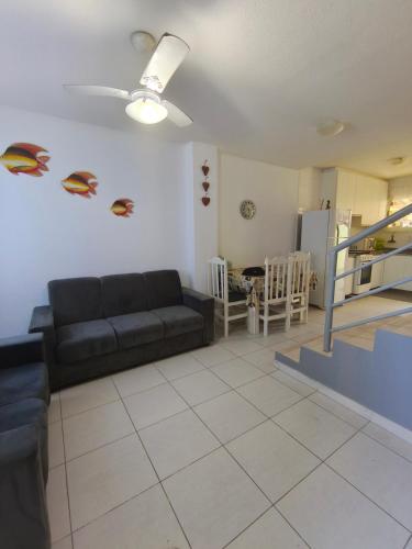 a living room with a black couch and a kitchen at Sobrado confortável a uma quadra do mar. in Matinhos
