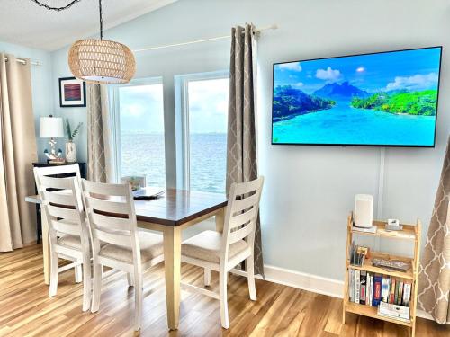 a dining room with a table and chairs with a tv on the wall at Oceanview Retreat with 60ft Seawall in Cudjoe Key