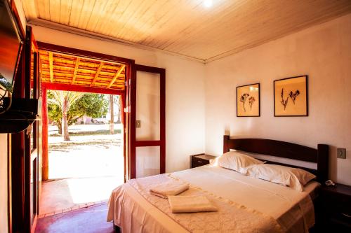 a bedroom with a bed and a sliding glass door at Hotel Fazenda Portal da Canastra in Zogaias