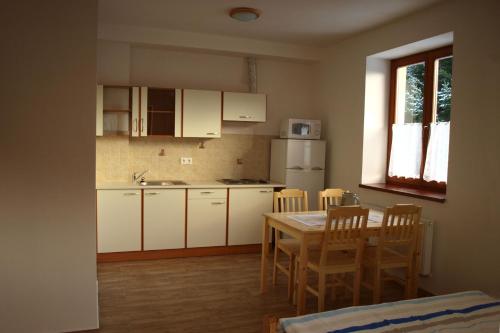 - une cuisine avec des placards blancs, une table et des chaises dans l'établissement HORSKÁ CHATA SOBÍK, à Dolní Morava