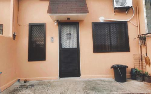 a house with a black door and a trash can at Wyne's Tiny House near Royal Farm Resort in Dipolog