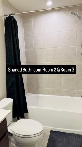 a bathroom with a white toilet and a bath tub at Abi home in Brandon