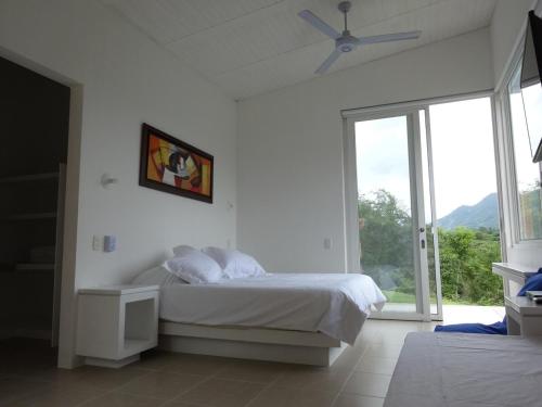 a white bedroom with a bed and a window at Villa Nirvana - Villeta in Payandé