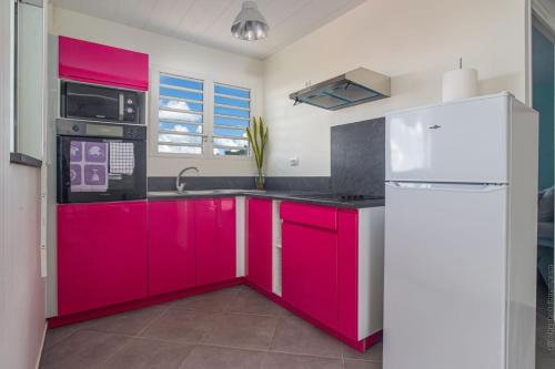 a kitchen with red cabinets and a white refrigerator at Les Villas Saint-Joseph in Rivière-Salée