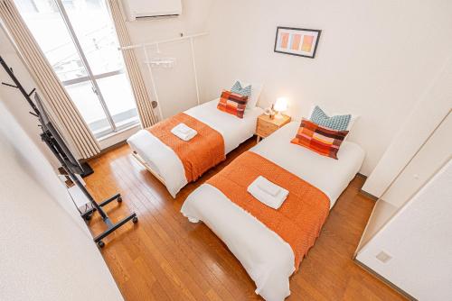 two beds in a room with a camera at Shinjuku Wind Apartment • Cozy Retreats in Tokyo