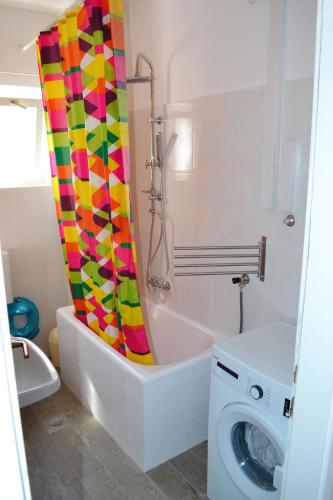 a bathroom with a shower curtain next to a washing machine at Apartment Vlado in Sukošan