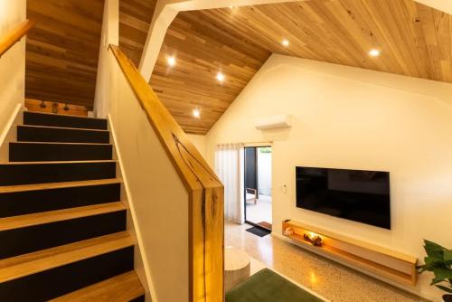 a living room with a staircase and a large tv at The Salted Shed - 650m to beach in Seaford