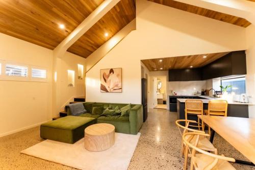 a living room with a green couch and a kitchen at The Salted Shed - 650m to beach in Seaford