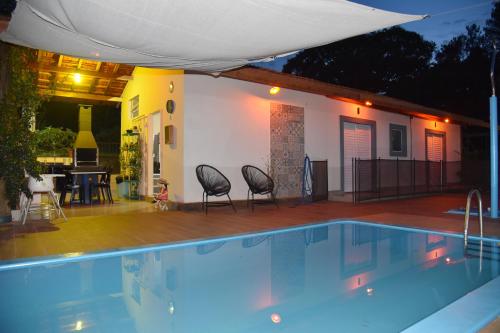 a swimming pool with chairs next to a house at Pousada Vossa Excelência in Cajuru